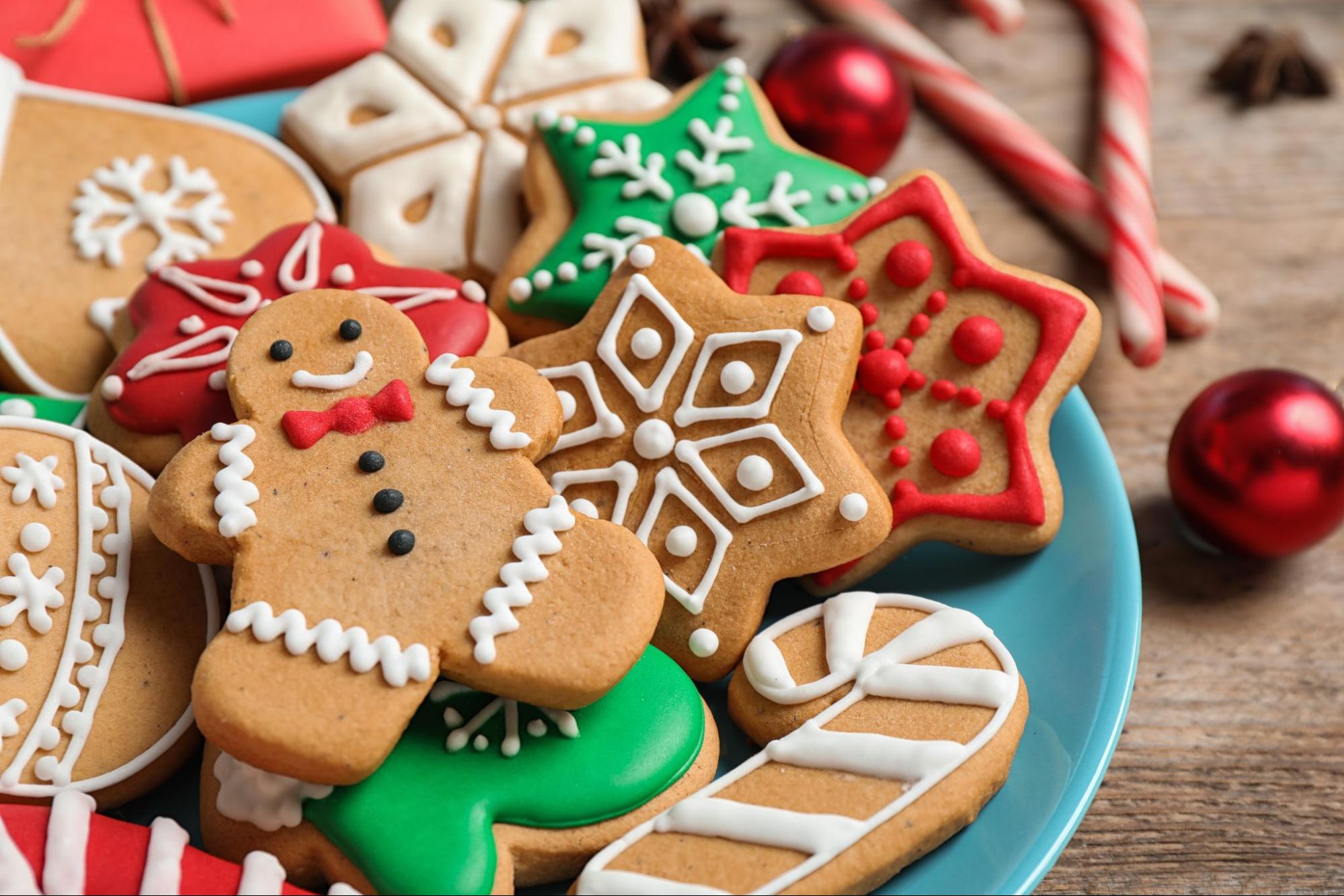 Gingerbread cookies decorated for the holidays, including a gingerbread man, snowflakes, and candy canes, on a blue plate, emphasizing festive treats suitable for braces-friendly recipes.